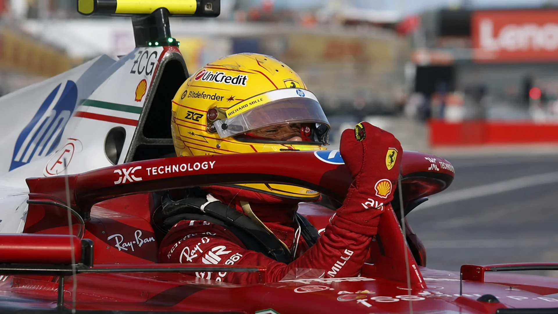 Lewis Hamilton zit met zijn helm op emotioneel in de cockpit van zijn rode Ferrari