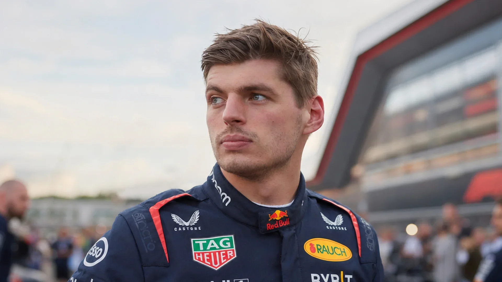 Max Verstappen kijkt bedachtzaam voor zich uit op de grid in Red Bull-overall