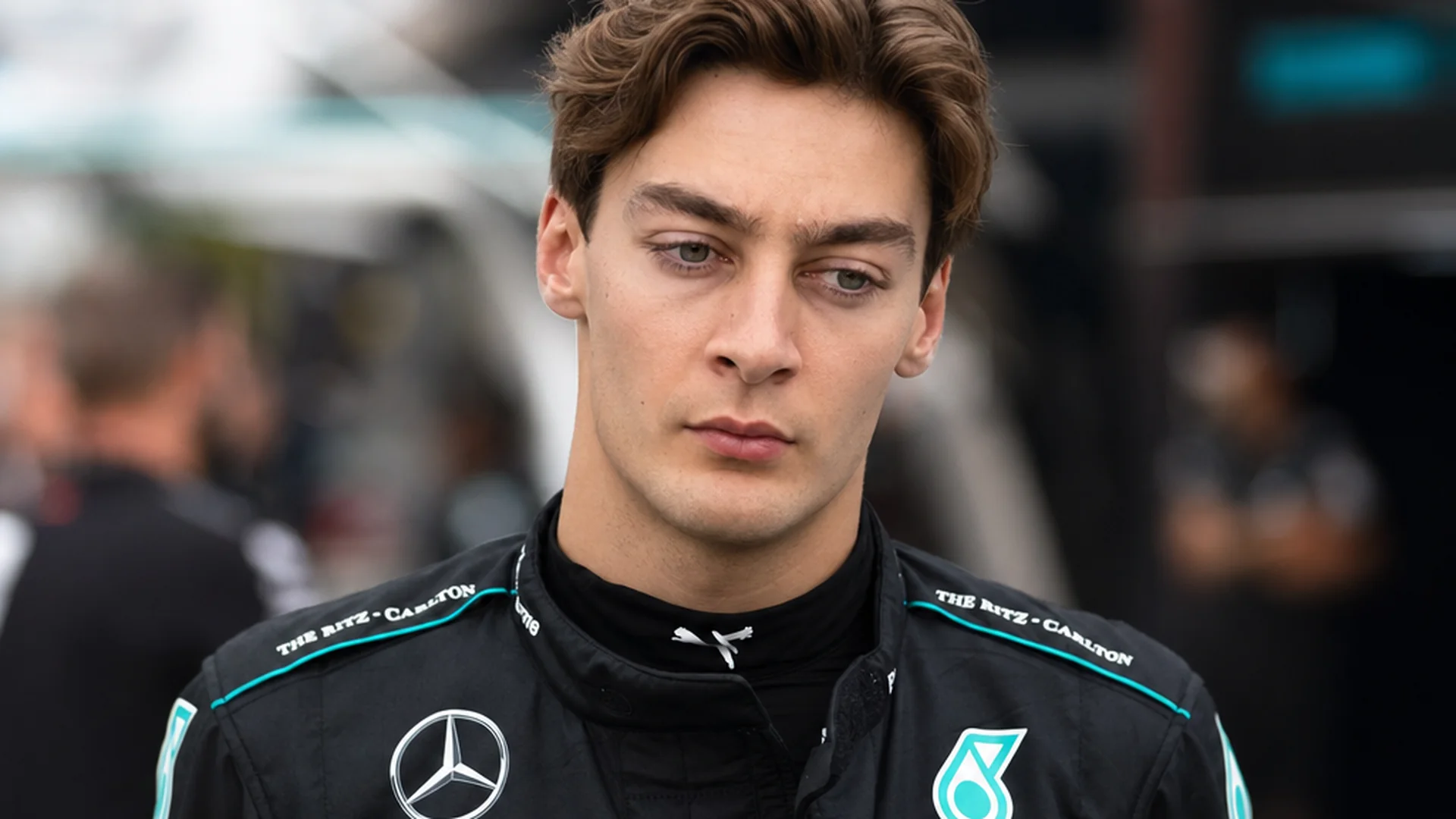 George Russell kijkt bedrukt voor zich uit in Mercedes-tenue in de paddock